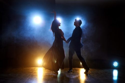 Skillful dancers performing in the dark room under the concert light and smoke. Sensual couple performing an artistic and emotional contemporary dance.